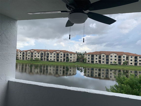 View from a balcony overlooking a lake and apartment buildings.