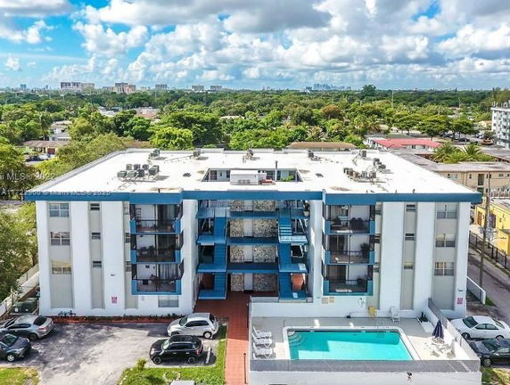 Front view of a multi-story apartment building with balconies and a swimming pool.
