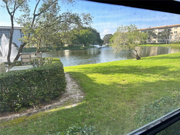 View of a lake with trees and a fountain, seen from a building window.