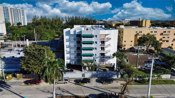 Front view of a multi-story building with balconies and green window awnings.