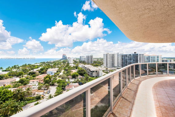 Panoramic view from a high-rise building balcony overlooking the city and ocean.