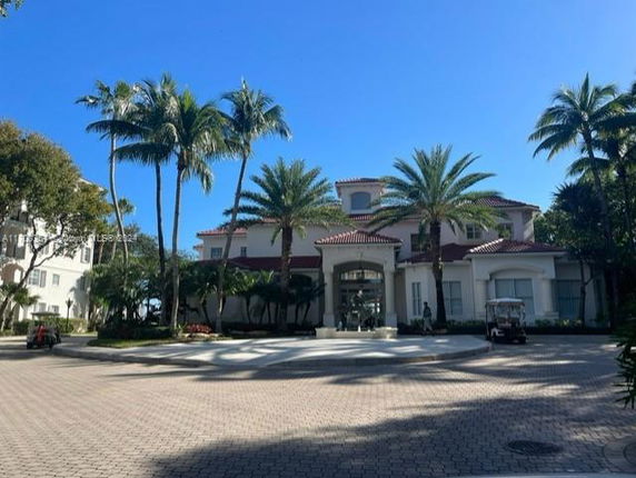Front view of a large multi-story building with palm trees around it.