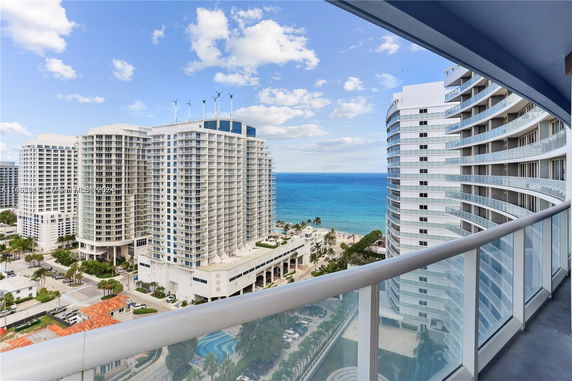 Panoramic view from a balcony overlooking high-rise buildings and ocean.