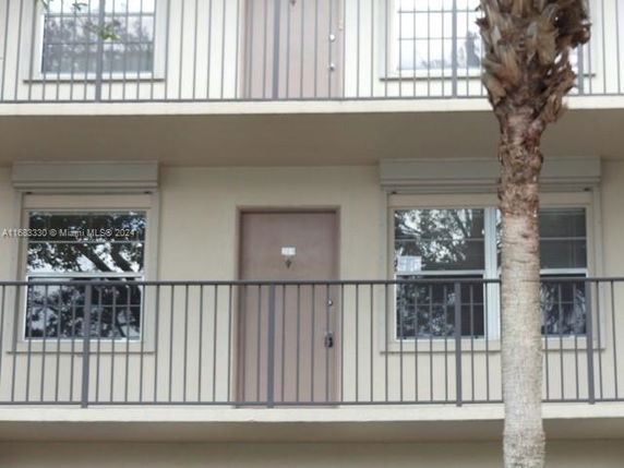 Front view of a multi-story building with balconies and doors.