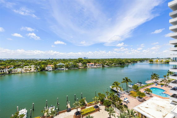 Panoramic view of waterfront residences and a wide river under a blue sky.