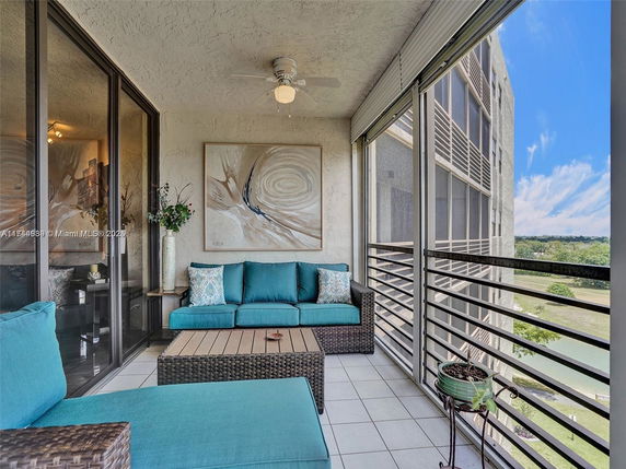 Balcony with rattan furniture and a view of surrounding buildings.