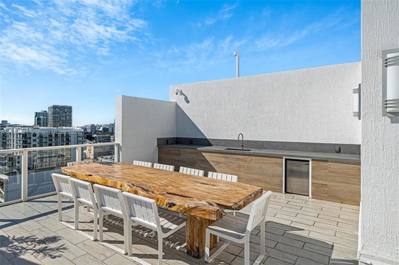 Rooftop with a wooden table, chairs, and a built-in counter with a sink and fridge.