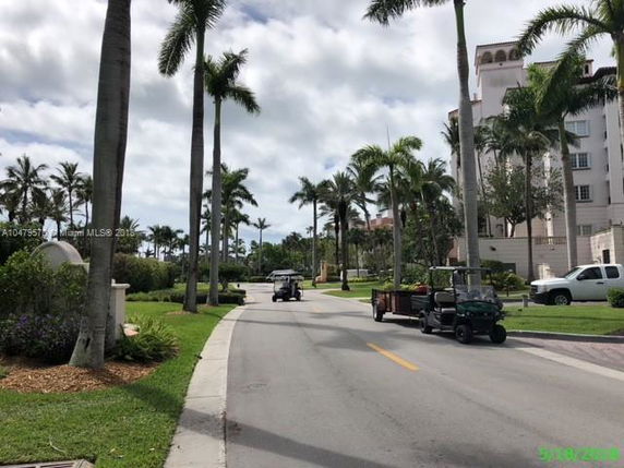 Street view lined with palm trees and a multi-story building.