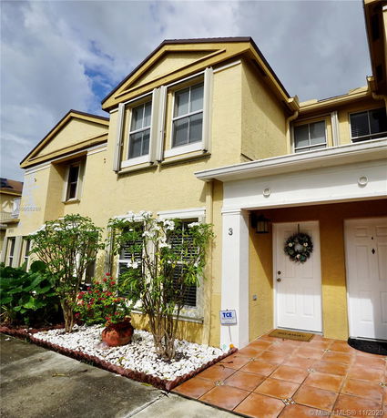 Front view of a two-story yellow house with a tiled entrance and white framed windows.