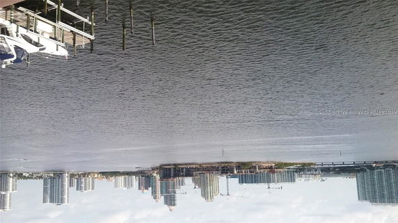 View of a city skyline across a body of water with boats docked in the foreground.
