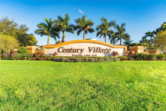Entrance sign of Century Village with landscaped surroundings.