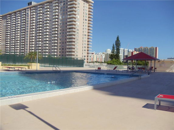 Rooftop swimming pool area with a view of a tall residential building in the background.