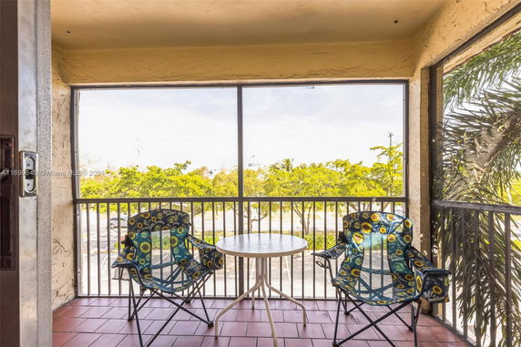 Balcony with two chairs and a table overlooking trees.