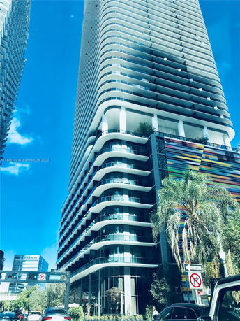 Front view of a modern high-rise building with curved balconies and colorful facade.