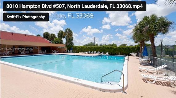 Outdoor swimming pool with surrounding lounge chairs and palm trees.