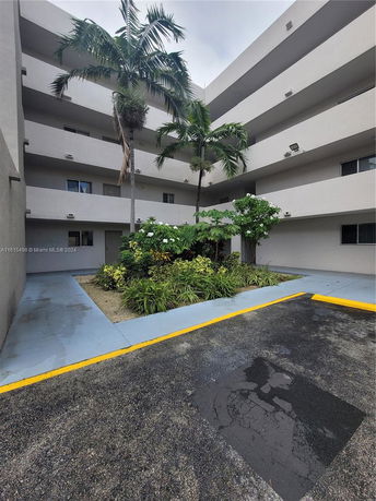 View of a multi-story building with balconies and tropical plants.