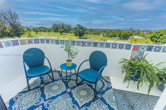 Balcony with blue chairs and decorative tiles overlooking a landscaped area.