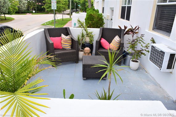 Outdoor seating area on a small terrace with plants and a view of the street.