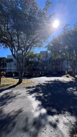 Front view of a multi-story residential building with balconies and a driveway.