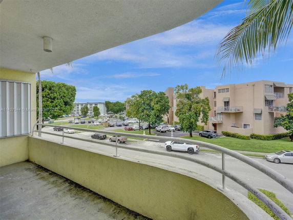 View from a balcony overlooking parking and residential buildings.