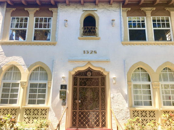 Front view of a two-story house with arched windows and decorative ironwork.