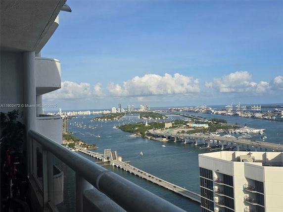 Panoramic view of a coastline and city skyline taken from a balcony of a high-rise building.