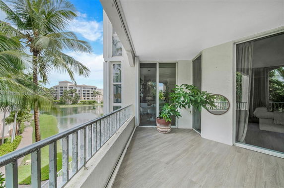 Balcony view overlooking a waterway with palm trees and adjacent buildings.