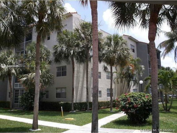 Front view of a multi-story residential building with palm trees.