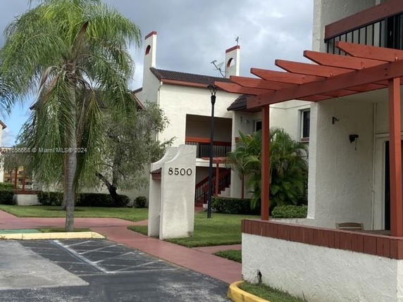 Front view of a residential building with a numbered pillar and a pergola-style entrance.