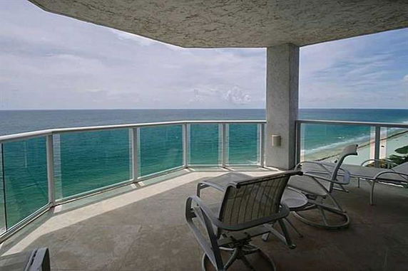 Panoramic view from a balcony with glass railings overlooking the ocean.