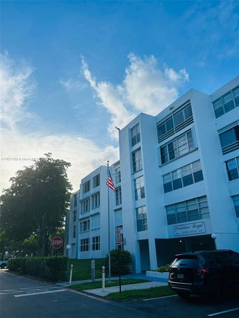Front view of a multi-story residential building with multiple windows and an American flag in front.