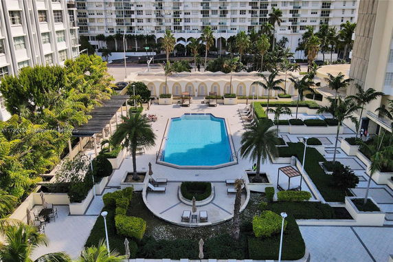 Outdoor view of a swimming pool area with surrounding greenery and seating.