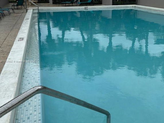 Outdoor swimming pool with a metal railing.