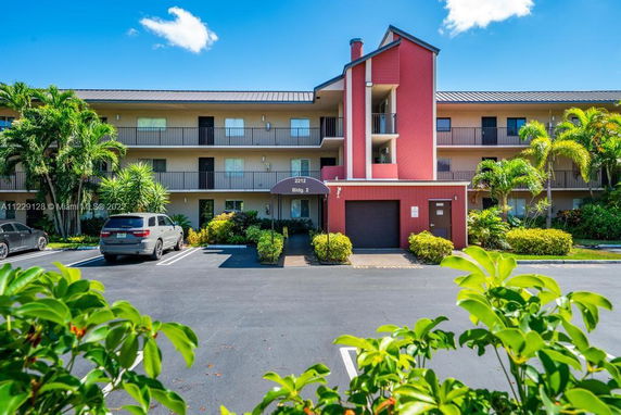 Front view of a three-story residential building with a red facade and a central entrance.
