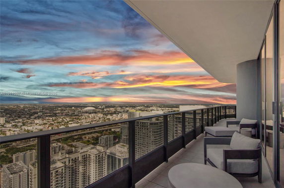 Balcony view showing cityscape and colorful sunset sky.
