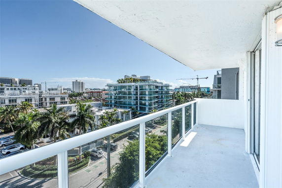 View from a balcony overlooking modern urban buildings and palm trees.