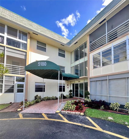 Front view of a multi-story building with a green awning and entryway.