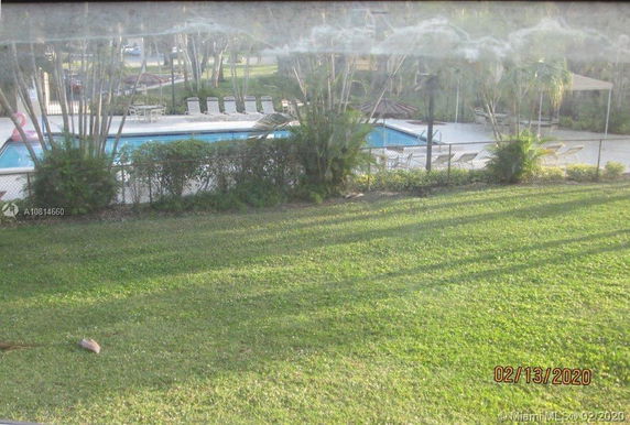 Outdoor view of a swimming pool area with surrounding greenery and lounge chairs.