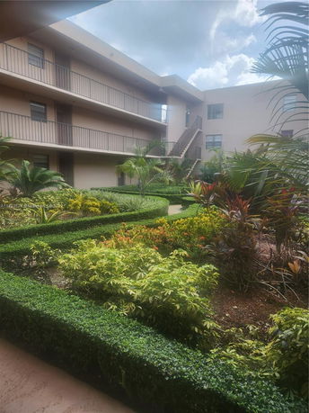 View of a multi-story building with an external staircase and landscaped garden.