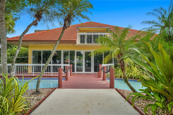 Front view of a house with a red tiled roof and a walkway over a small water feature.