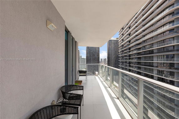 Balcony with outdoor seating and high-rise buildings in the background.