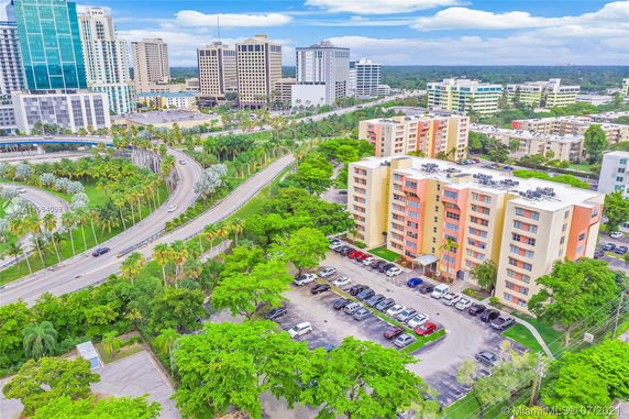 Aerial view of urban area with multiple mid-rise buildings and roads surrounded by greenery.