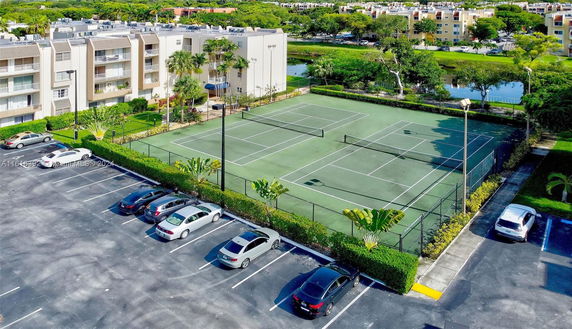 Tennis courts adjacent to an apartment building with nearby parking area.