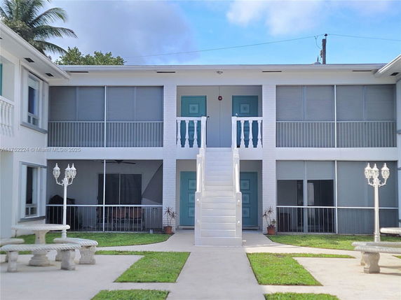 Front view of a two-story building with a central staircase and screened balconies.