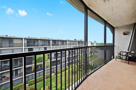 Balcony view overlooking a multi-story apartment building with screened balconies.