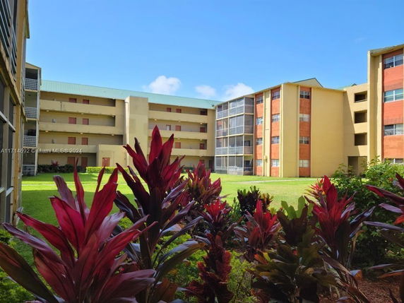 View of multi-story apartment buildings with visible balconies and greenery in the foreground.