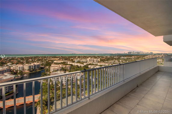 Wide angle view from a high balcony overlooking a cityscape and distant skyline at sunset.