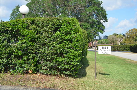 Entrance area with a sign for Jacaranda Villas and surrounding greenery.