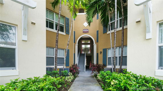 Entrance view of an apartment building with a central archway and stairs.