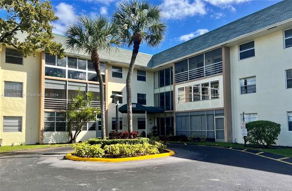 Front view of a three-story residential building with large windows and a green awning over the entrance.